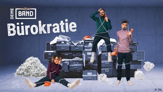 Grafik zum Deine-Band-Song 9 (Bürokratie) mit den Mitgliedern der Band ok.danke.tschüss. Das Bild zeigt einen fensterlosen Raum mit Betonwänden, in dessen Mitte mehrere Schubladenschränke stehen. Überall schauen kreuz und quer Papiere heraus. Eva sitzt mit ausgestreckten Beinen auf dem Boden vor den Schränken, Lucas mittig darauf und Manu steht rechts davor. Alle drei halten sich jeweils den orangen Hörer eines analogen Telefons ans Ohr und sind im Telefonkabel verheddert. Links von Eva ein Haufen aus geschredderten Papierschnipseln, auf dem Boden zusammengeknülltes Papier. Links oben das Logo des Projekts DEINE BAND, darunter in großer Schrift der Titel des Songs: Bürokratie. (Quelle: DW)